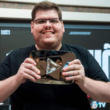 Casimiro Miguel, criador da CazéTV, sorrindo e segurando placa do YouTube em estúdio esportivo durante gravação de conteúdo digital.