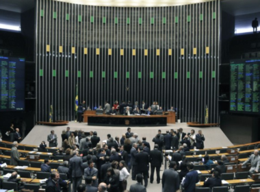 Vista geral do Plenário Ulysses Guimarães na Câmara dos Deputados, em Brasília, mostrando deputados federais reunidos em sessão com os painéis eletrônicos de votação acesos ao fundo.