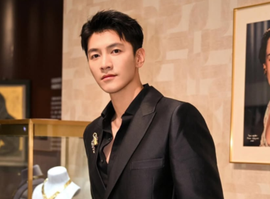 Ator chinês Jin Ze posa usando terno preto elegante em ambiente sofisticado, durante evento ligado ao universo dos doramas. O artista aparece em destaque diante de obras de arte e decoração de luxo.