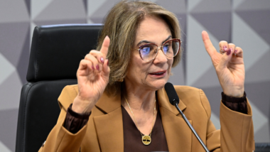 Damares Alves gesticula durante audiência no Senado Federal, usando blazer bege e óculos, enquanto fala ao microfone em sessão parlamentar sobre temas políticos.