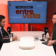 Kim Kataguiri participa de entrevista no programa Simplificando, da DiaTV, conduzida por Gui Sampaio. O deputado federal aparece à esquerda, de terno e gravata, enquanto o apresentador está à direita, em frente aos microfones, em um estúdio com iluminação vermelha e um monitor ao fundo exibindo a identidade visual do programa "Simplificando Entrevista".