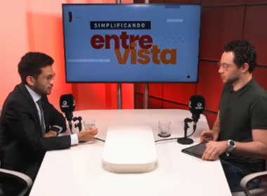 Kim Kataguiri participa de entrevista no programa Simplificando, da DiaTV, conduzida por Gui Sampaio. O deputado federal aparece à esquerda, de terno e gravata, enquanto o apresentador está à direita, em frente aos microfones, em um estúdio com iluminação vermelha e um monitor ao fundo exibindo a identidade visual do programa "Simplificando Entrevista".