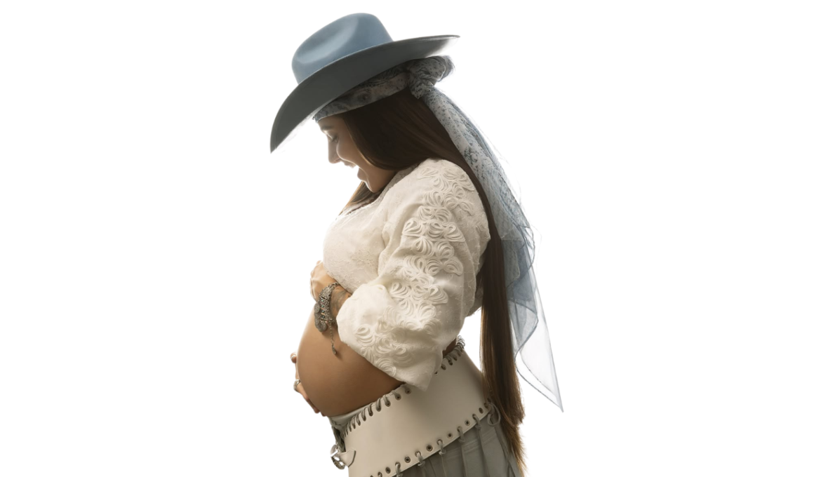 Lauana Prado posa de perfil exibindo a barriga de gravidez em ensaio fotográfico com fundo branco, usando chapéu azul-claro, blusa branca rendada e saia clara, em anúncio do nascimento do primeiro filho e lançamento de nova música.
