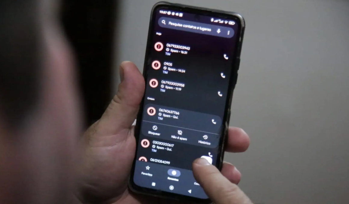 Homem mechendo no celular enquanto se depara com ligação de spam